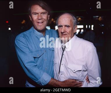 Glen Campbell and his uncle William Eugene 'Boo' Campbell share a moment at Glen Campbell's surprise 60th birthday party in Branson, Missouri on April 21, 1996. Glen Campbell's actual birth date was April 22, 1936. He died of complications from Alzheimer's disease on August 8, 2017. 'Uncle Boo' is credited by Glen Campbell for teaching him to play guitar as a boy. Stock Photo