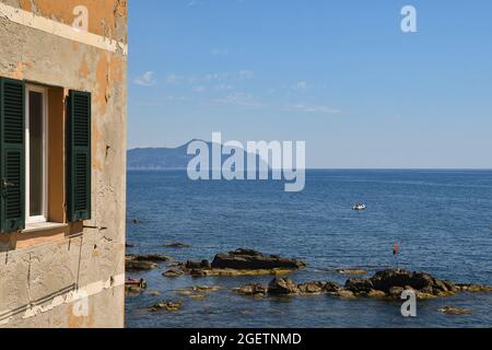 An old house overlooking the sea in the old fishing village with the promontory of Portofino on the horizon over water, Boccadasse, Genoa, Liguria Stock Photo