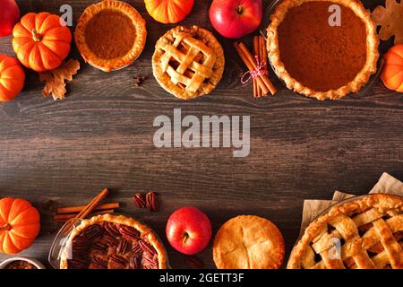 Variety of homemade autumn pies. Pumpkin, apple and pecan. Above view double border over a rustic wood background with copy space. Stock Photo