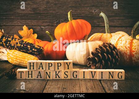 Happy Thanksgiving greeting on wooden blocks against a rustic wood background with pumpkins and autumn decor. Vintage style. Stock Photo