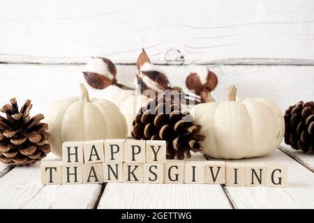 Happy Thanksgiving greeting on wooden blocks against a white wood background with white pumpkins and brown autumn decor Stock Photo