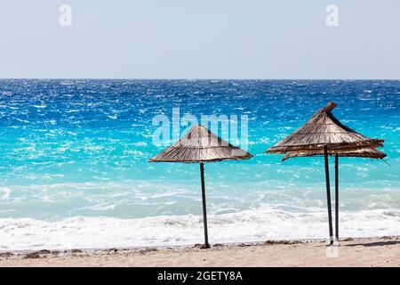 The rows of straw umbrellas on empty beach. Blue sky and turquoise sea. Albanian riviera. Albania, Europe Stock Photo