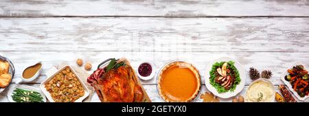 Classic Thanksgiving turkey dinner. Above view bottom border on a rustic white wood banner background with copy space. Turkey, mashed potatoes, stuffi Stock Photo