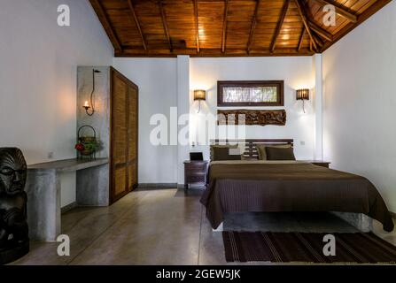 Tangalle, Sri Lanka – Oct 31, 2017: Inside hotel or residential house, room with bed, wooden furniture and ceiling. Bedroom home interior in Indian mi