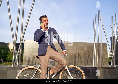 Middle-aged man talking on the phone leaning on his white bicycle. High quality photo Stock Photo