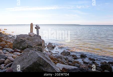 Stones balance, zen pebbles stack over blue sea in Estonia. Blue sky on sunny coast in summer. Stock Photo