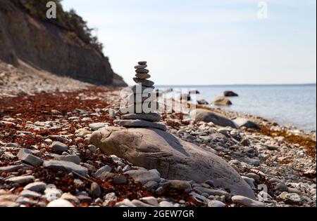 Stones balance, zen pebbles stack over blue sea in Estonia. Blue sky on sunny coast in summer. Stock Photo