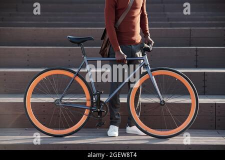 Low section of black guy with bicycle standing against staircase outdoors Stock Photo