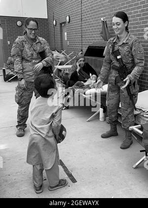 KABUL, AFGHANISTAN - Specialist Julie Bailey & Sergeant Breanna Jessop with XVIII Airborne Corps' 82nd Airborne Division play catch with an Afghan child at Hamid Karzai International Airport, August 20. Stock Photo