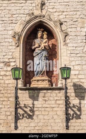 Gent, Flanders, Belgium - July 30, 2021: Closeup of colored stone statue of madonna with child set in niche of beige brick facade of Vleeshuis, the me Stock Photo