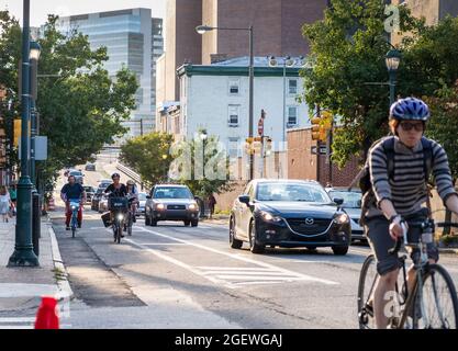 Cyclists commuting on city streets bike lanes with cars and traffic, University City, Philadelphia, Pennsylvania, USA Stock Photo