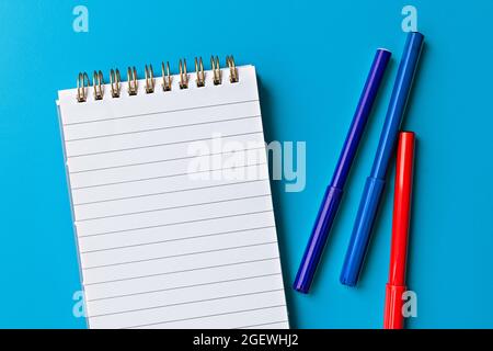 template for text and design. empty white notepad and multi-colored markers on light blue background Stock Photo