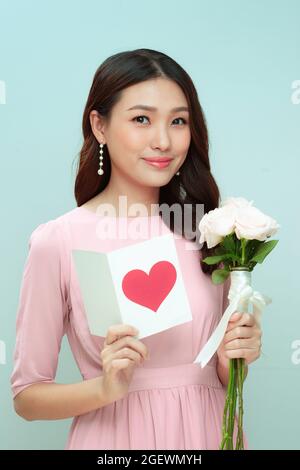 Young blond woman with smile holding floral bouquet and greeting card Stock Photo