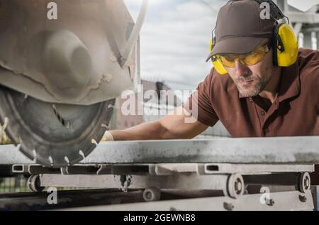 Concrete Outdoor Path Tile Cutting by Professional Caucasian Worker Wearing Safety Glasses. Outdoor Architecture Industry Theme. Stock Photo