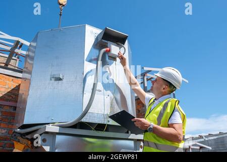 Engineer with clipboard checking the installation of the ventilation system Stock Photo