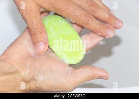 A man washes his hands with a green soap Stock Photo