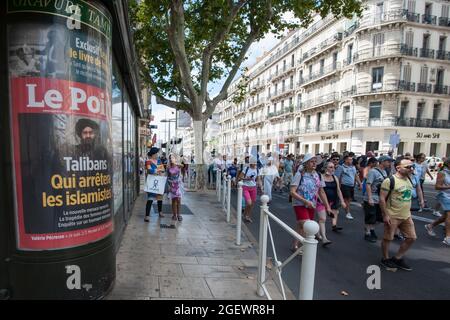 Demonstrators are seen passing a poster of the French newspaper 'Le Point' which headlines the Taliban takeover in Afghanistan, during the protest.Saturday 21 August 2021 is the sixth day of mobilization against the vaccine policy and the application of the health pass. In Toulon (Var), according to the authorities there were 6000 demonstrators. The main slogans criticize the government decisions as dictatorial. Some of the placards included signs and slogans comparing the current situation with the Nazi regime and the Second World War. Stock Photo