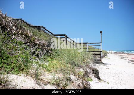 A wooden  access pier to the white sandy beach of the Florida coast Stock Photo