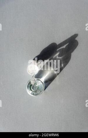 Bottle of Hyaluronic acid gel with pipette on light grey background. Trendy selfcare products. Sharp shadows, top view. Stock Photo