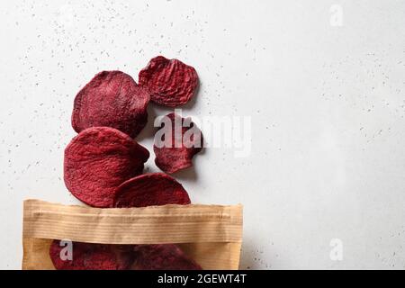 Vegetable beetroot chips in paper craft package on a white background. Vegan snack. View from above. Stock Photo