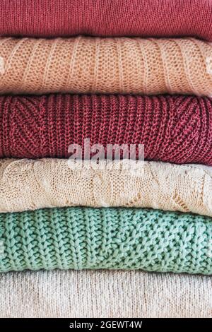 Stack of warm cozy knitted women's sweaters. Cozy autumn or winter clothes. Background. Stock Photo