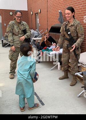 KABUL, AFGHANISTAN - Specialist Julie Bailey & Sergeant Breanna Jessop with XVIII Airborne Corps' 82nd Airborne Division play catch with an Afghan child at Hamid Karzai International Airport, August 20. Stock Photo