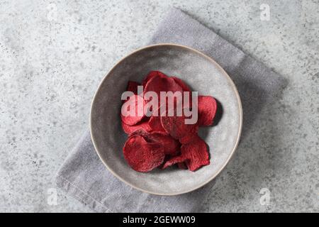 Vegetable beetroot chips in gray bowl on a gray background. Vegan snack. Top view. Stock Photo