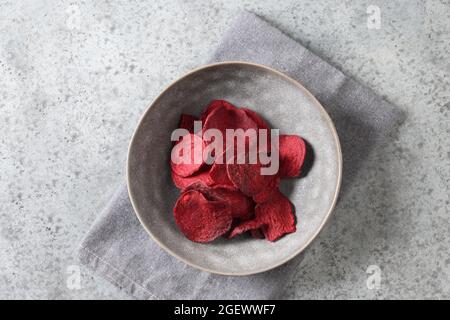 Vegetable beetroot chips in gray bowl on a gray background. Vegan snack. Top view. Stock Photo