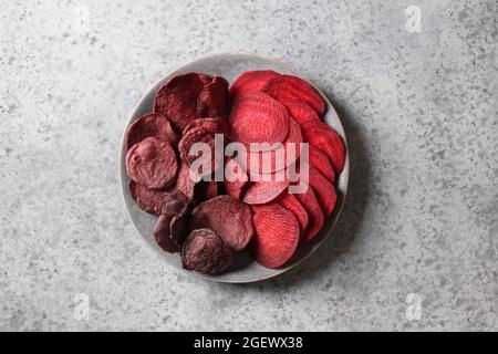 Vegetable beetroot dry and fresh chips in plate on a gray background. Top view. Healthy vegan snack. Stock Photo