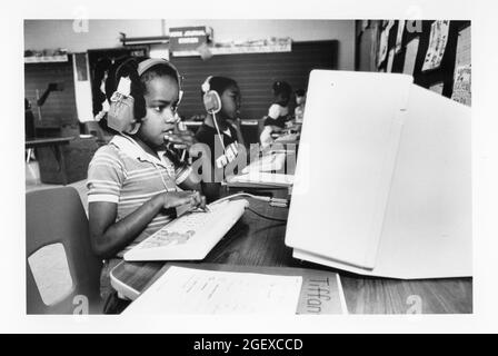 Austin Texas USA, circa 1990: First grade students use headphones to listen to computer-based instructional program on how to write stories. ©Bob Daemmrich Stock Photo