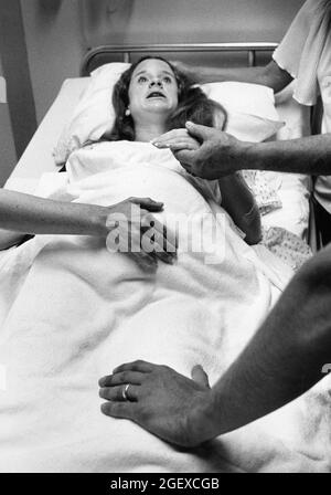 Austin Texas USA, 1982: Childbirth story that ran in the Austin American-Statesman in 1982. While labor and delivery nurses look on, husband clasps his pregnant wife's hand while she struggles through a contraction during labor in the hospital. File 82-48 Box #12  birth was 6-2-1982.  ©Bob Daemmrich Stock Photo