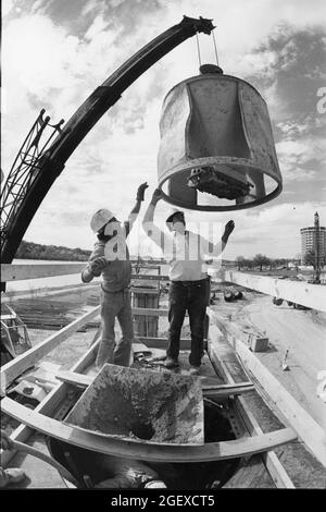 Austin Texas USA, circa 1984: Workers wearing hard hats guide unit into place during bridge construction on Interstate 35 near downtown. ©Bob Daemmrich Stock Photo