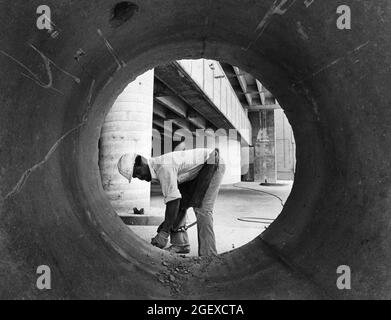 Austin Texas USA, circa 1984: Man wearing hard hat works on sewer construction project on Congress Avenue. ©Bob Daemmrich Stock Photo