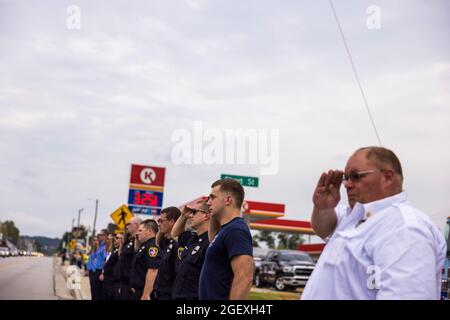 SPENCER, INDIANA - AUGEST 18: Firefighters render honors during the funeral procession of fallen paramedic Brandon Staley on August 18, 2021 on W. Morgan Street in Spencer, Indiana. Staley died from a heart attack while working as a paramedic for Owen County EMS. Staley had just responded to a vehicle accident and was in an ambulance with crash survivors helping them on the way to a hospital when he himself became ill. Stock Photo