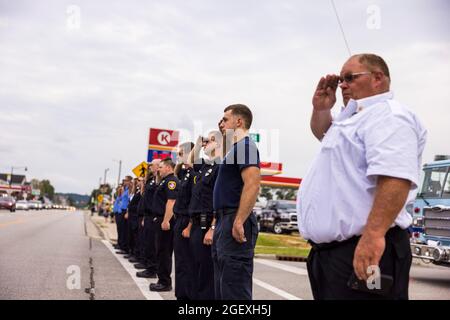 SPENCER, INDIANA - AUGEST 18: Firefighters render honors during the funeral procession of fallen paramedic Brandon Staley on August 18, 2021 on W. Morgan Street in Spencer, Indiana. Staley died from a heart attack while working as a paramedic for Owen County EMS. Staley had just responded to a vehicle accident and was in an ambulance with crash survivors helping them on the way to a hospital when he himself became ill. Stock Photo