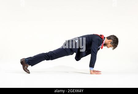 Businessman in stylish suit working out with push-ups in a full length side view on white in a fitness and healthy active lifestyle concept Stock Photo