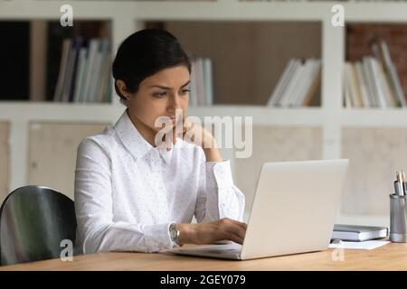Serious thoughtful Indian woman working on laptop Stock Photo
