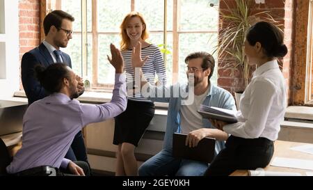 Multiracial employees giving high five during group briefing in office Stock Photo