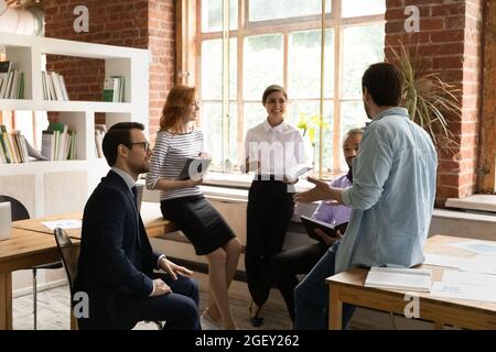 Five employees gather in morning briefing led by Caucasian executive Stock Photo