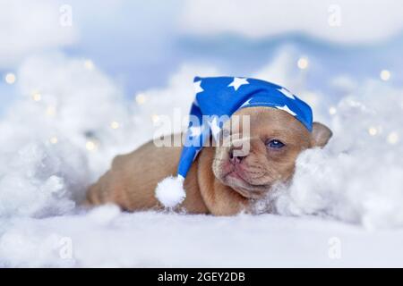 Sleepy French Bulldog puppy with nightcap lying between fluffy clouds and stars