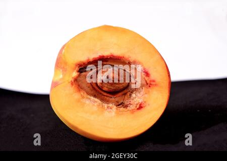 Beautiful peach half with seed isolated on black and white background Stock Photo