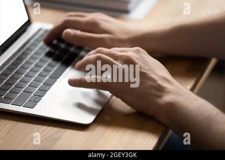 Closeup man hands typing on modern laptop at office desk Stock Photo
