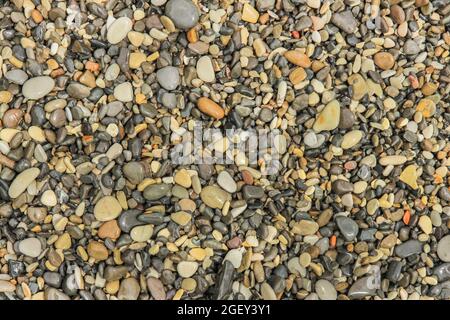 Wet pebbles on the shore in bulk as a background Stock Photo