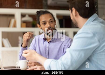 Diverse male workmates discussing collaborative task sit in office workplace Stock Photo