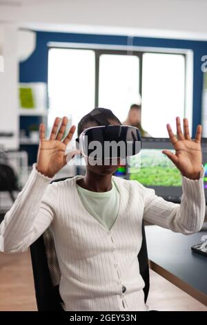 African video video maker experiencing VR headset, gesturing, editing video film montage working at footage and sound on computer with two displays. Videographer processing movie in creative agency Stock Photo