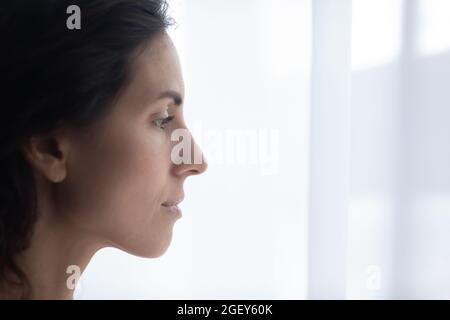 Closeup face of Hispanic sad woman standing indoor near window Stock Photo