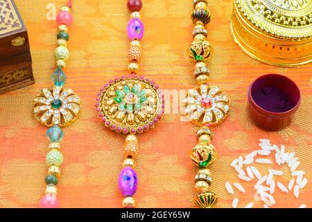 Celebrating Indian hindu festival Raksha Bandhan. Colorful Rakhi with kumkum and rice on a gold colored silk background Stock Photo