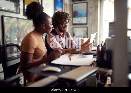 two young colleagues, male and female, different race, working together in the office. Antiracist concept Stock Photo