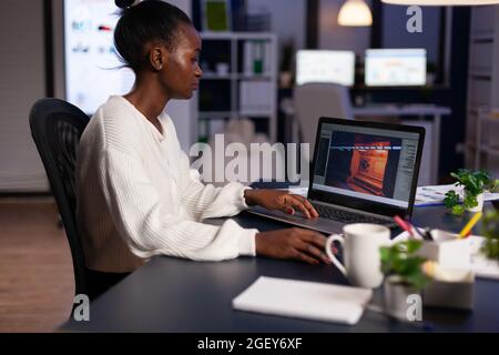 African american game developer testing new game working late at night in creativity agency company. Tired creator designer developing online video games on pc using modern production technology Stock Photo