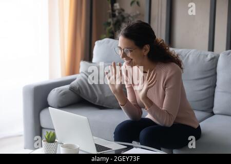 Happy woman looks at laptop greeting friend start video call Stock Photo